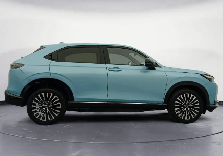Vue de profil côté gauche d'un Honda e:Ny1 204 ch Advance bleu électrique avec jantes stylisées en étoile.