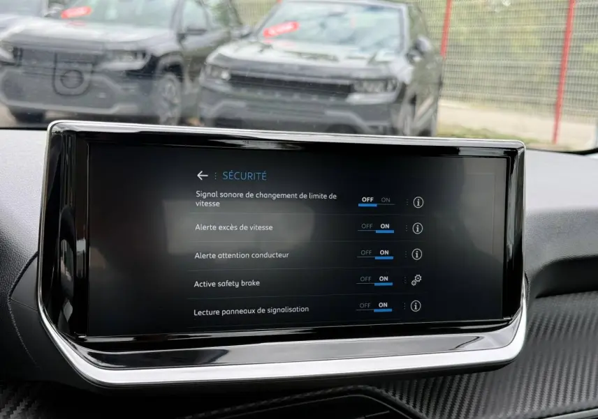 Écran tactile central de la Peugeot 208 noir Perla Nera, vue intérieure avant avec menu sécurité affiché.