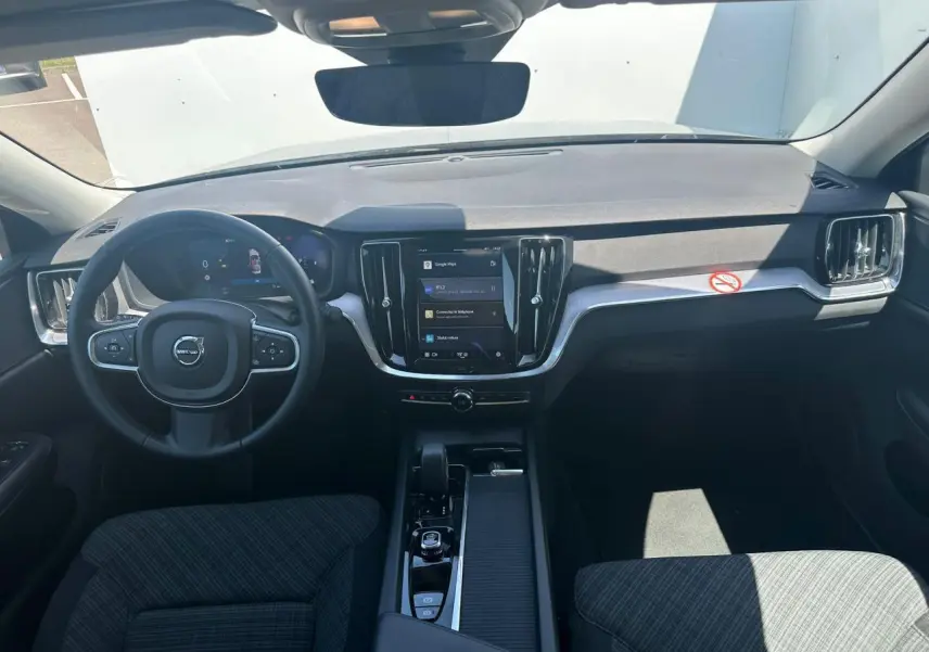 Vue intérieure avant du tableau de bord et volant noir de la Volvo S60 2024 avec écran tactile central vertical.