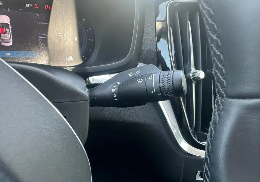 Gros plan sur la commande d'essuie-glace à gauche du volant dans l'habitacle noir du Volvo S60 2024 Thunder Grey Metal