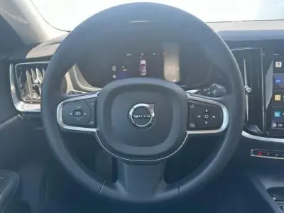 Volant noir en simili-cuir de Volvo S60 2024 avec commandes intégrées et tableau de bord digital visible derrière.
