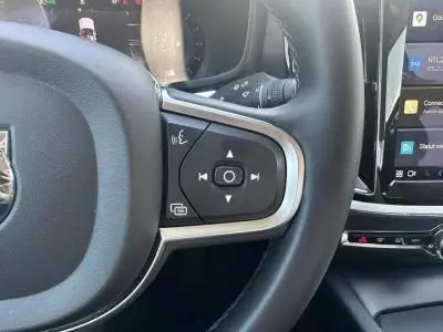 Gros plan sur les commandes audio au volant noir et argenté d'une Volvo S60 Thunder Grey 2024, intérieur moderne.