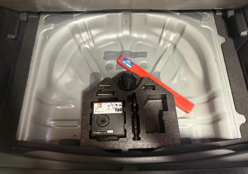 Coffre ouvert d'une CUPRA Formentor gris magnétique, vue plongeante sur le rangement sous plancher avec kit de réparation.