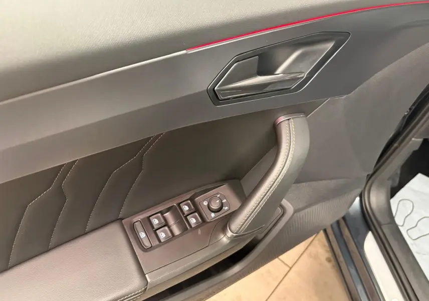 Gros plan sur la porte avant gauche de la CUPRA Formentor gris magnétique, montrant les commandes des vitres et la poignée intérieure.