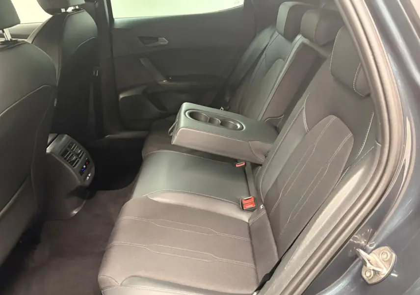 Vue côté droit de l’arrière du CUPRA Formentor gris magnétique, montrant les sièges noirs avec accoudoir central et porte-gobelets.