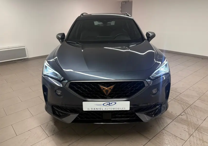 Vue avant d'un CUPRA Formentor gris magnétique 2024 avec calandre noire et feux LED allumés en intérieur.
