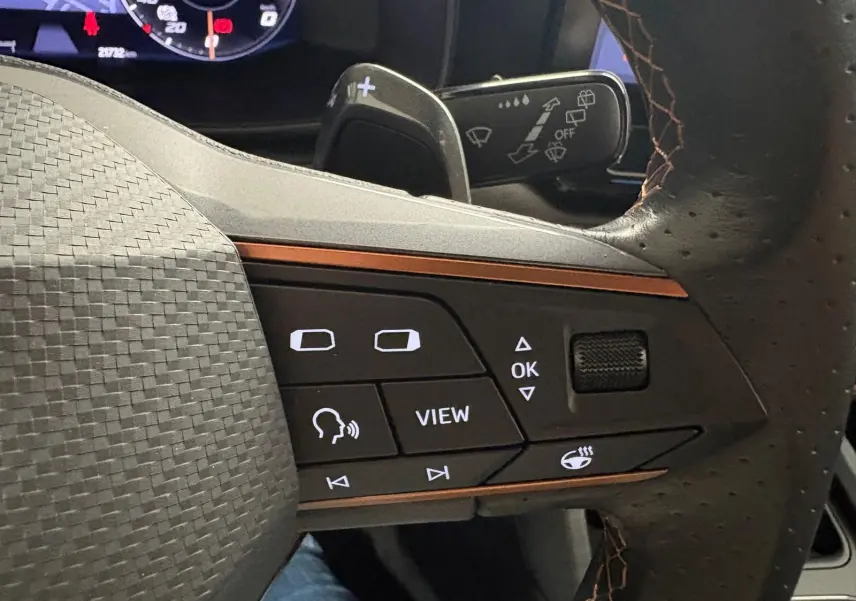 Gros plan sur les commandes du volant cuir perforé avec surpiqûres marron du CUPRA Formentor gris magnétique 2024.