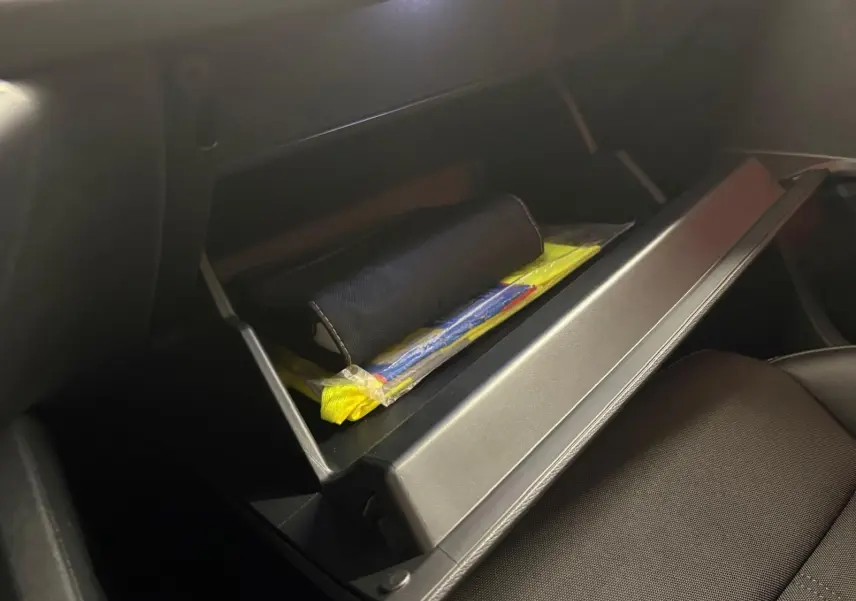 Gros plan sur la boîte à gants ouverte du CUPRA Formentor 2024, contenant des documents et accessoires, intérieur noir.