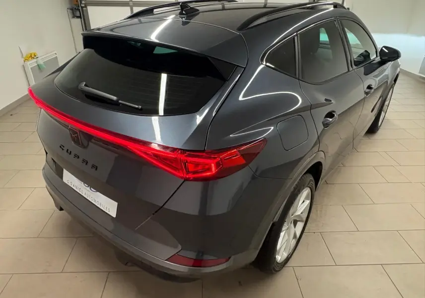 Vue 3/4 arrière droite du CUPRA Formentor gris magnétique 2024 avec feux arrière allumés et toit noir brillant.