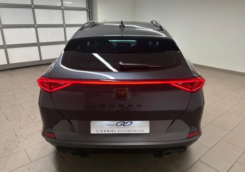 Vue arrière du CUPRA Formentor 1.5 TSI gris magnétique avec feux LED allumés dans un garage.