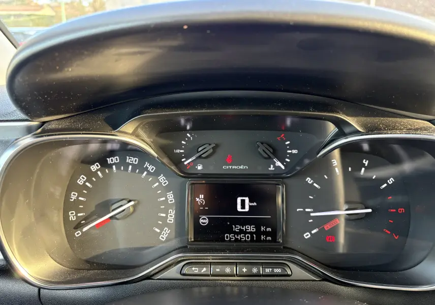 Vue rapprochée du tableau de bord de la Citroën C3 rouge, affichant les compteurs et l'écran digital central.