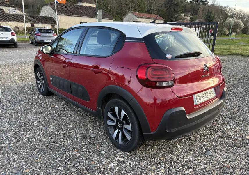 Vue 3/4 arrière droite d'une Citroën C3 rouge avec toit blanc, Airbump noir sur porte et jantes alliage.