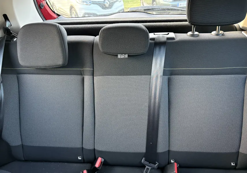 Vue intérieure sur la banquette arrière grise et noire d'une Citroën C3 rouge, avec appuie-têtes et ceinture de sécurité visible.