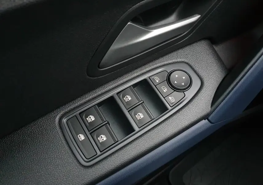 Gros plan sur les commandes de lève-vitres et rétroviseurs côté conducteur du Dacia Duster blanc glacier 2025.