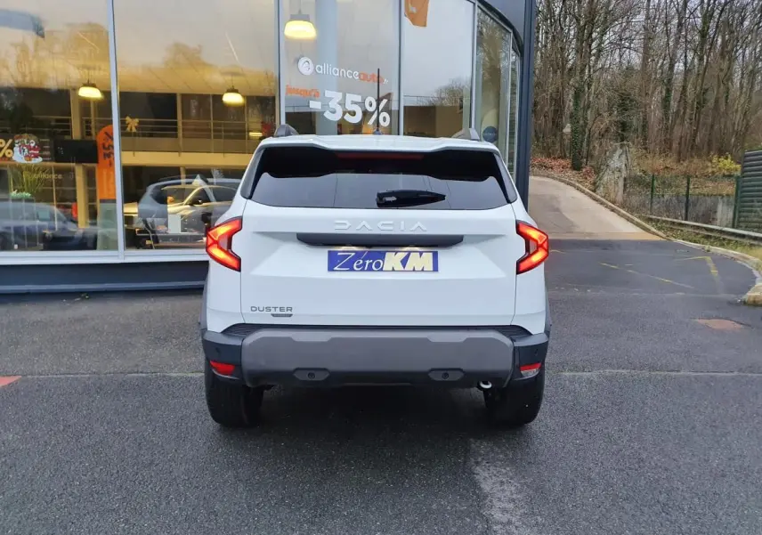 Vue arrière d'un Dacia Duster blanc glacier 2025 avec feux LED en forme de C et vitres arrière surteintées.