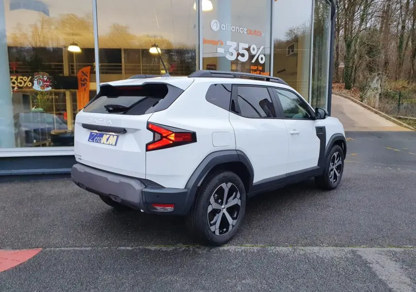 Vue 3/4 arrière droit du Dacia Duster 1.6 Hybrid 140 blanc glacier avec jantes alliage 18" diamantées.