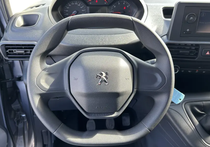 Vue rapprochée du volant Peugeot noir du Dangel Partner 4x4 gris Artense, avec tableau de bord et console centrale visibles.