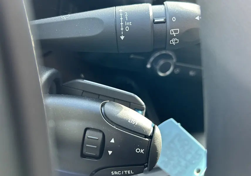 Gros plan sur les commandes au volant du DANGEL Peugeot Partner 4x4 gris Artense, montrant les boutons de réglage et de liste.