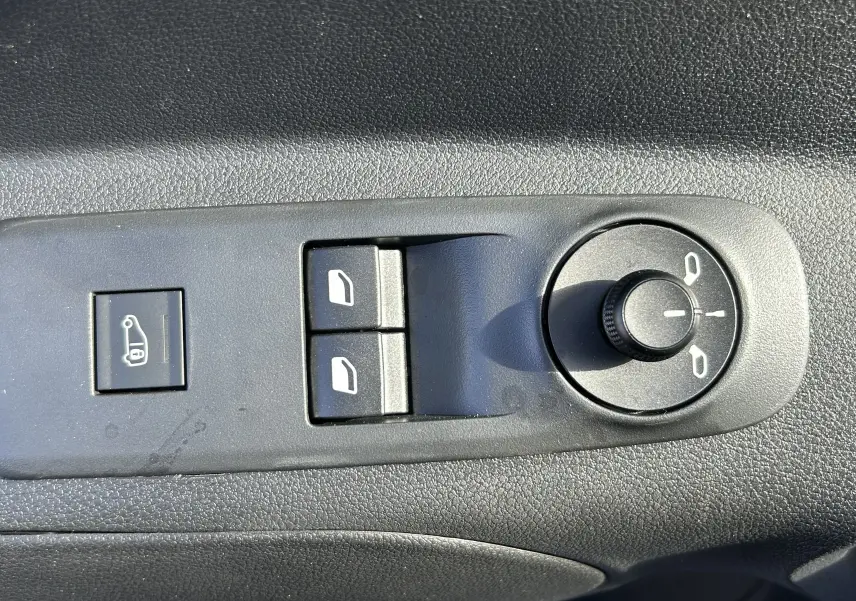 Gros plan sur les commandes de réglage des rétroviseurs et des vitres électriques côté conducteur du DANGEL Peugeot Partner gris Artense.
