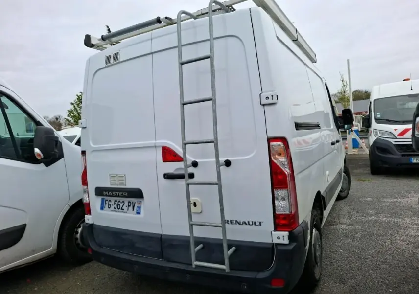 Vue arrière d'un Renault Master blanc 2019 avec échelle métallique fixée sur la porte et galerie sur le toit.