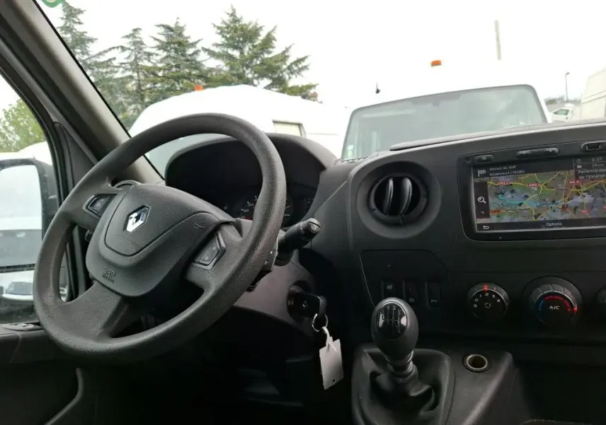 Vue intérieure côté conducteur du Renault Master blanc 2019, montrant le volant, levier de vitesse manuel et écran GPS intégré.