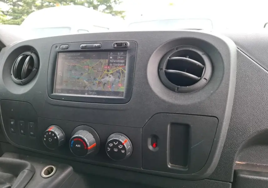 Vue rapprochée de la console centrale du Renault Master blanc, avec écran GPS et commandes de climatisation visibles.