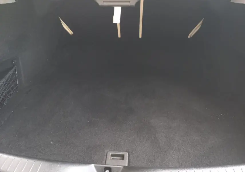 Coffre vide en vue plongeante d'une Mercedes Classe C Coupé blanc, intérieur noir avec filet de rangement latéral.