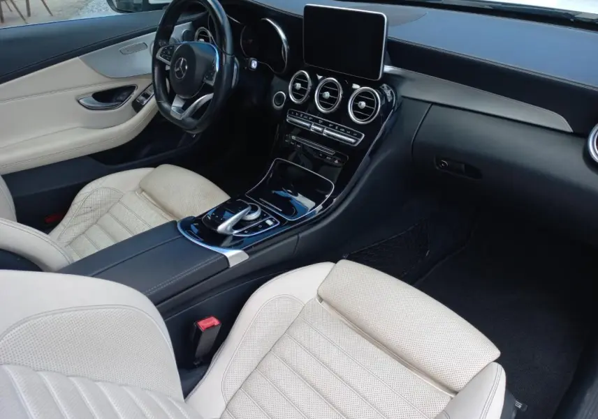 Vue intérieure côté conducteur de la Mercedes Classe C Coupé 2016, sièges cuir beige et tableau de bord noir brillant.