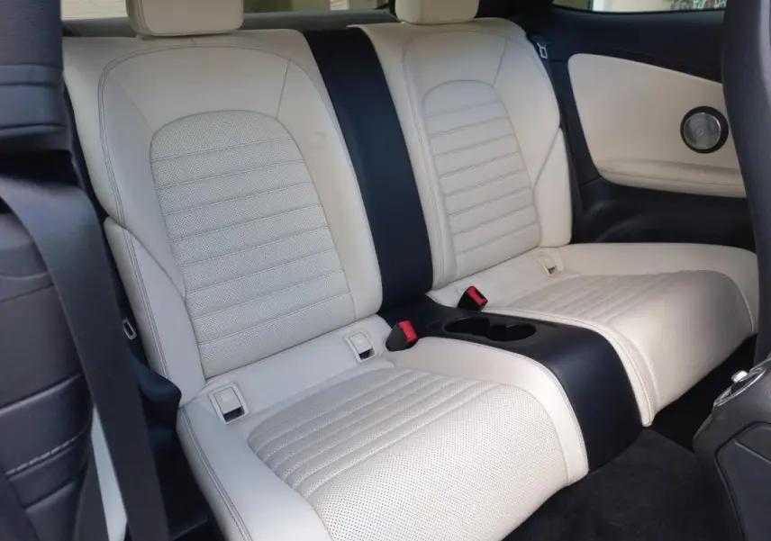 Vue intérieure arrière montrant les sièges en cuir beige clair avec accoudoir central et ceinture noire d'une Mercedes Classe C Coupé.
