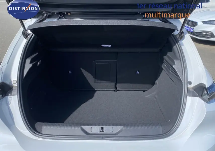 Coffre ouvert vu de l'arrière d'une Peugeot 308 Hybrid 145ch GT blanche, montrant un espace de chargement propre et spacieux.