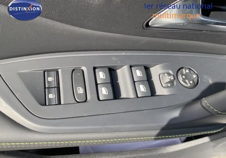Vue rapprochée des commandes de lève-vitres et rétroviseurs sur la porte côté conducteur d’une Peugeot 308 Hybrid blanche.