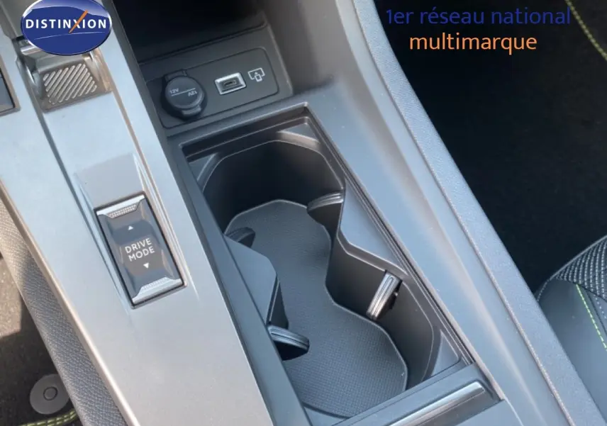Gros plan sur la console centrale noire de la Peugeot 308 Hybrid 145ch, montrant porte-gobelets et bouton Drive Mode.