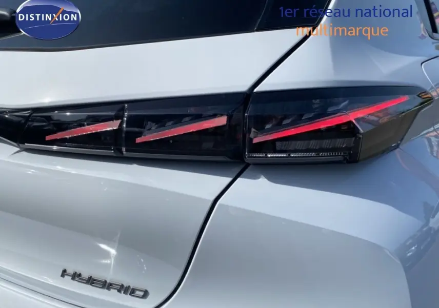 Gros plan sur le feu arrière droit et le logo HYBRID d'une Peugeot 308 blanche Okenite Metal, vue arrière.