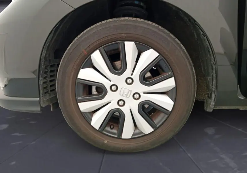 Gros plan sur la roue avant gauche noire d'une Honda Jazz 2024 E:HEV avec jante à design moderne bicolore.