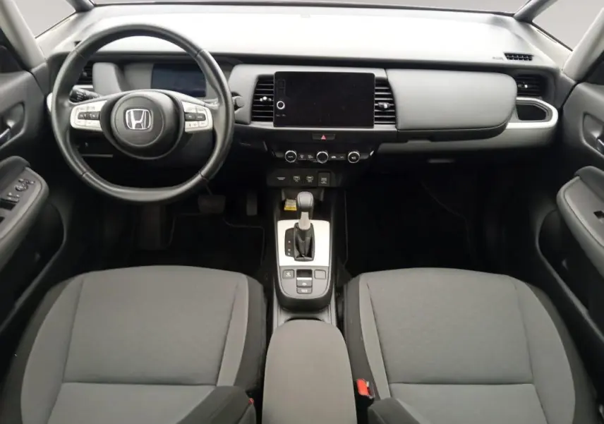 Vue intérieure avant de la Honda Jazz 2024 E:HEV Advance, tableau de bord noir avec écran tactile central et volant multifonction.