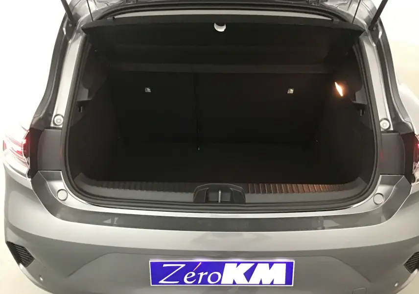 Coffre ouvert vu de l'arrière d'une Renault Clio V gris schiste avec éclairage intérieur et plaque Zéro KM visible.