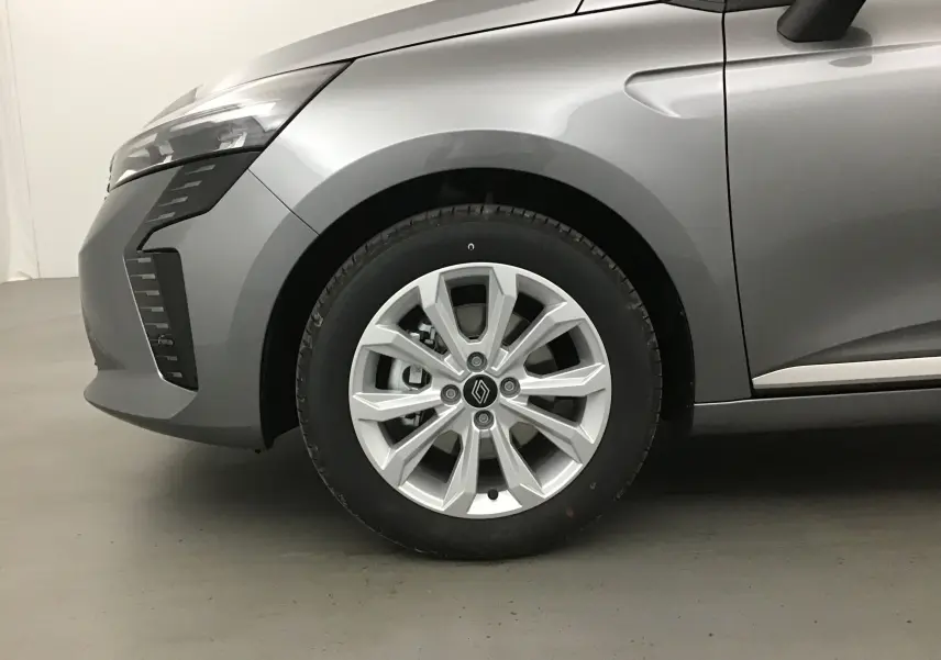 Gros plan sur la roue avant gauche d'une Renault Clio V gris schiste, mettant en valeur la jante alu 16 pouces et la carrosserie lisse.