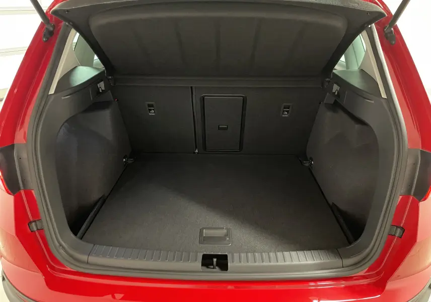 Coffre ouvert vu de l'arrière d'un SEAT Ateca 2024 Rouge Velvet, montrant un espace de chargement propre et spacieux.