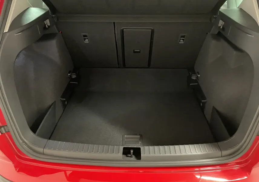 Coffre ouvert d'un SEAT Ateca 2024 Rouge Velvet, vue arrière montrant l'espace de chargement vide et les finitions intérieures noires.