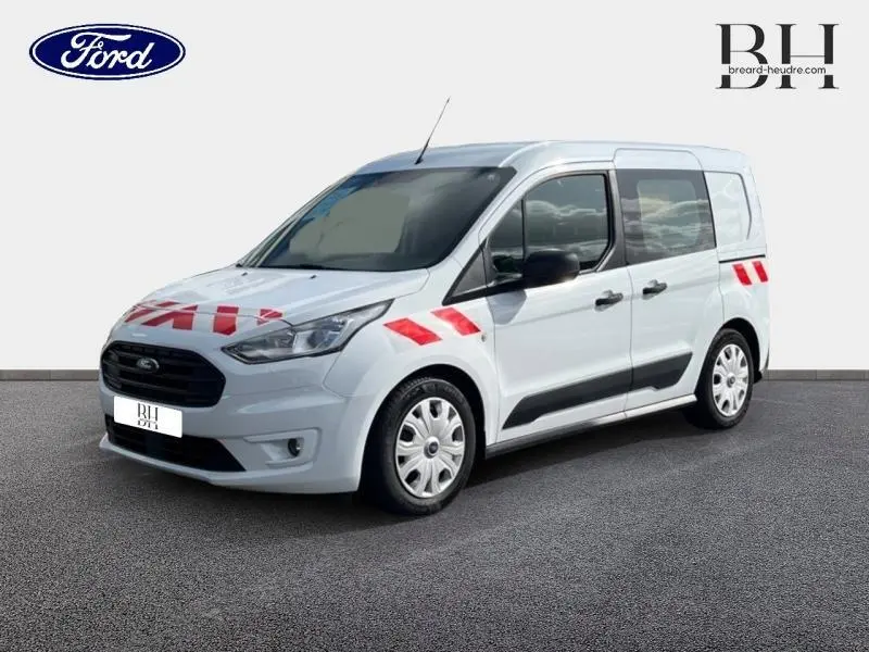 Ford Transit Connect L1 blanc glacier vu en 3/4 avant droit avec marquages rouges de sécurité sur la carrosserie.