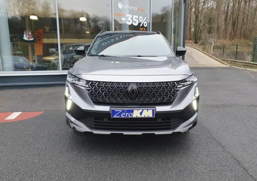 Vue de face du Renault Austral gris schiste avec calandre noire et feux LED allumés, toit panoramique noir visible.