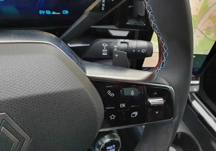 Gros plan sur le volant Alcantara avec surpiqûres tricolores et commandes multifonctions du Renault Austral hybride 2025.