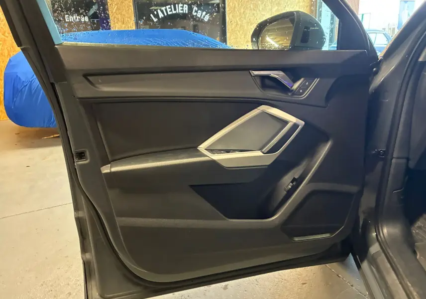 Vue intérieure de la porte avant gauche gris foncé de l'Audi Q3 Sportback avec insert argenté et commandes électriques.