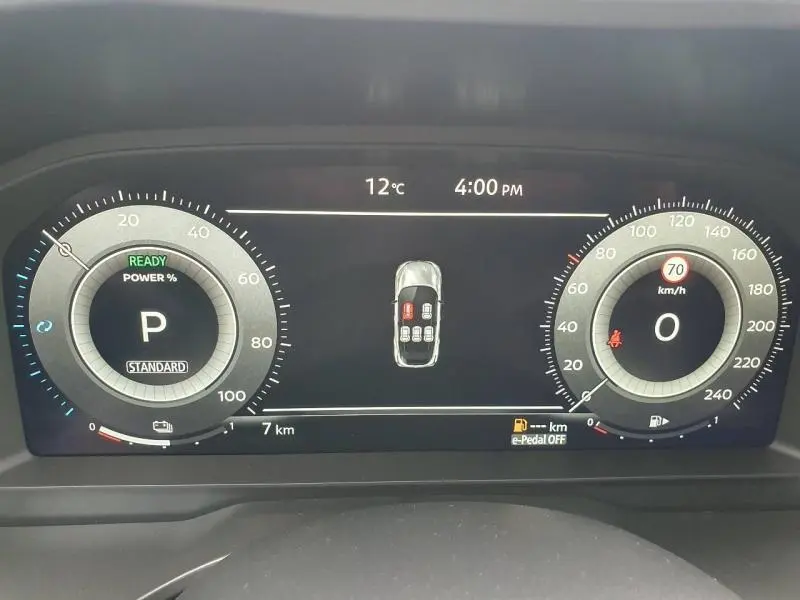 Tableau de bord numérique du Nissan Qashqai Hybrid e-POWER gris, affichant vitesse, température et état des portes ouvertes.