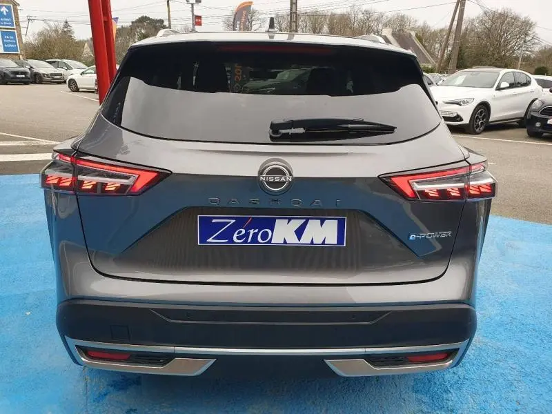 Vue arrière du Nissan Qashqai Hybrid e-POWER 205ch gris Squale métallisé avec feux LED allumés sur parking.
