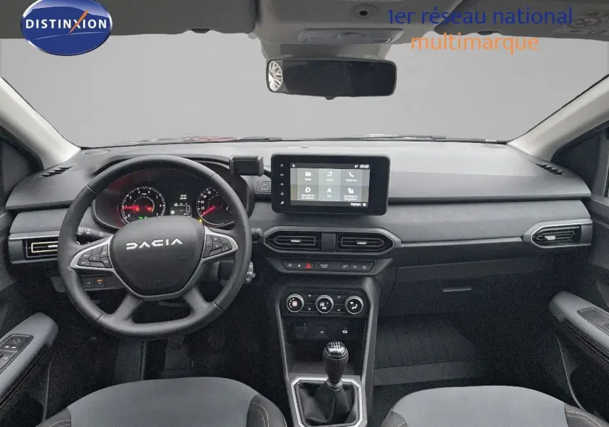 Vue intérieure avant du tableau de bord et volant noir du Dacia Jogger gris schiste métal avec écran tactile central et boîte manuelle.