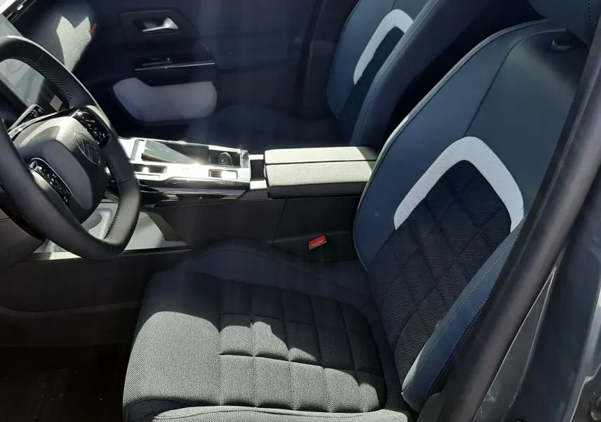 Vue intérieure côté conducteur du Citroën C5 Aircross 2026, sièges tissu gris noir avec inserts clairs et console centrale moderne.