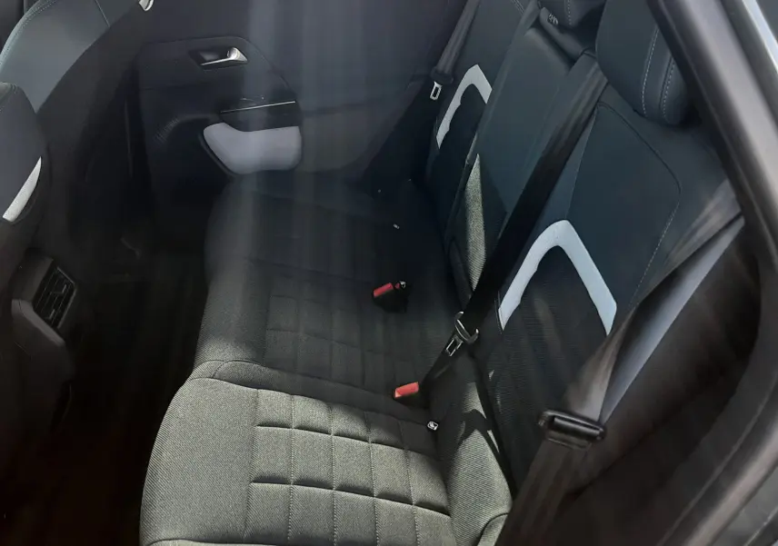Vue intérieure côté arrière droit du Citroën C5 Aircross 2026, sièges gris noir avec détails blancs et ceintures noires.