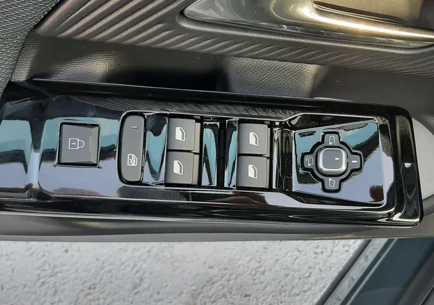 Gros plan sur les commandes de lève-vitres et rétroviseurs côté gauche du Citroën C5 Aircross vert Astoria avec intérieur noir.