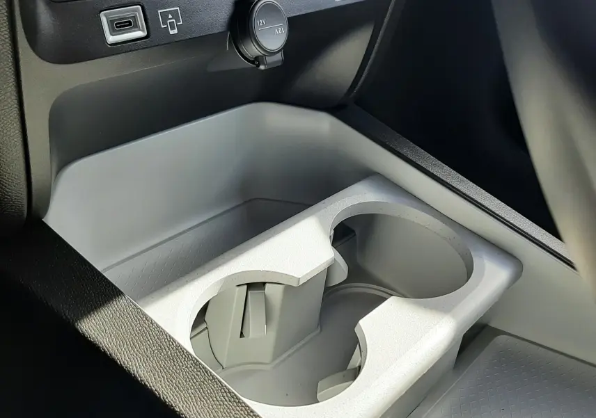 Gros plan sur la console centrale grise du Citroën C5 Aircross 2026, avec porte-gobelets et prises USB et 12V visibles.